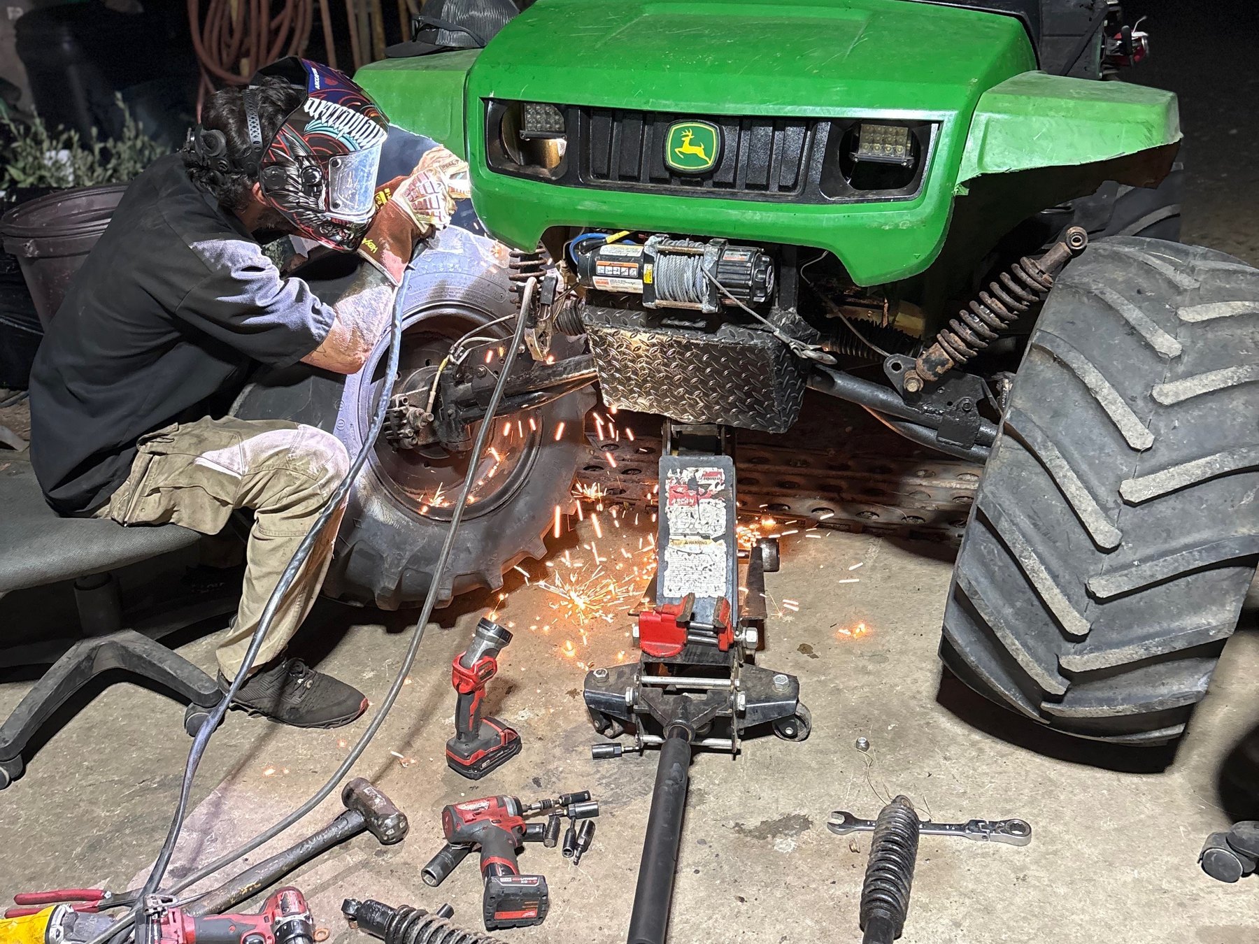 Technician welding on a piece of equipment with tools laid out on the shop floor