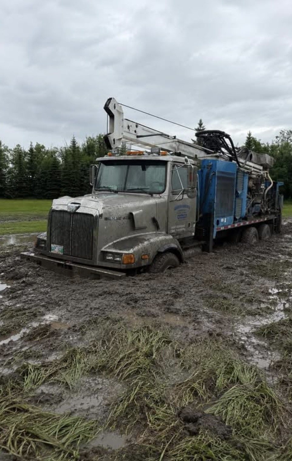 Heavy truck-mounted equipment parked in a muddy field